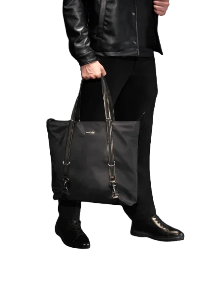 Person holding a black tote bag with a visible brand logo