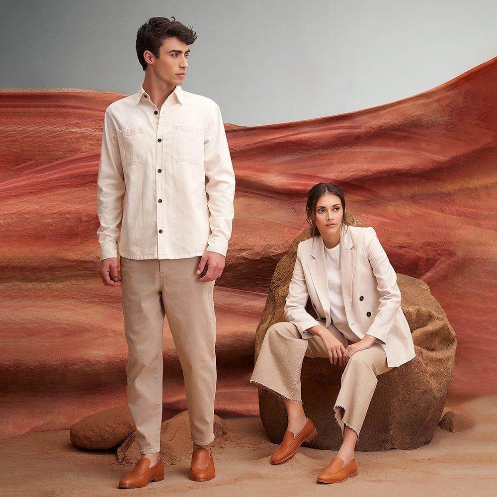 Man and woman in neutral outfits wearing tan leather loafers, desert-inspired backdrop