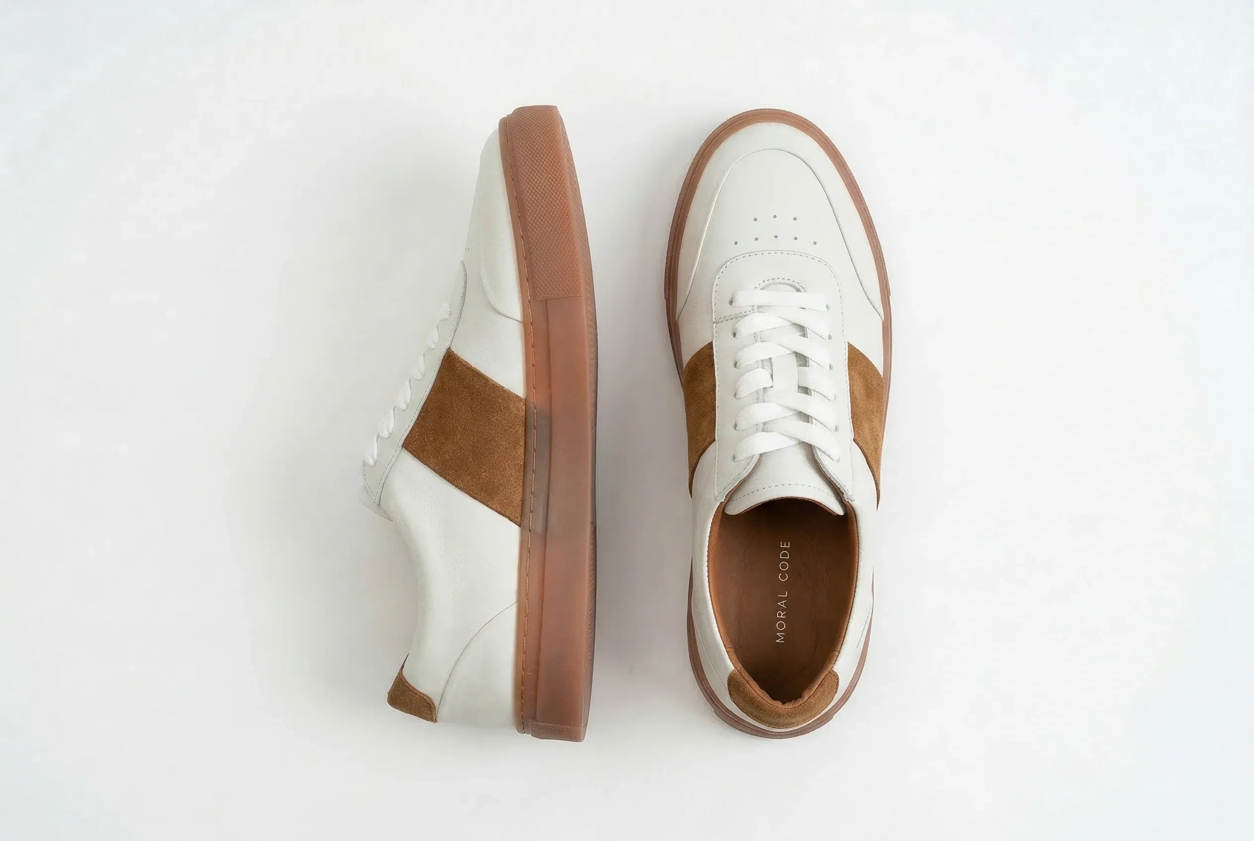 Men's white leather sneakers with brown suede accents and gum soles on white background