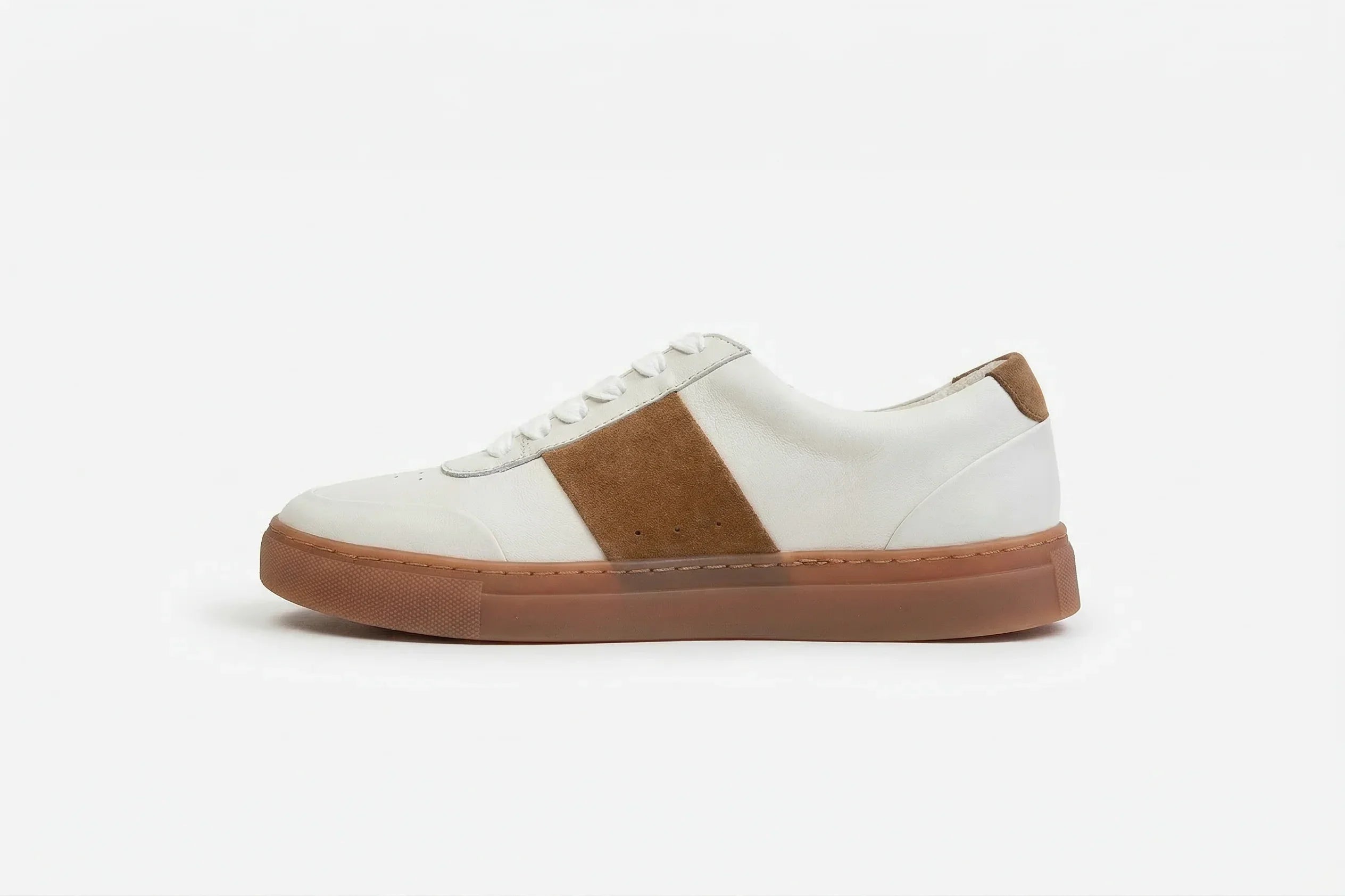 White leather sneaker with tan suede accent and brown rubber sole on white background