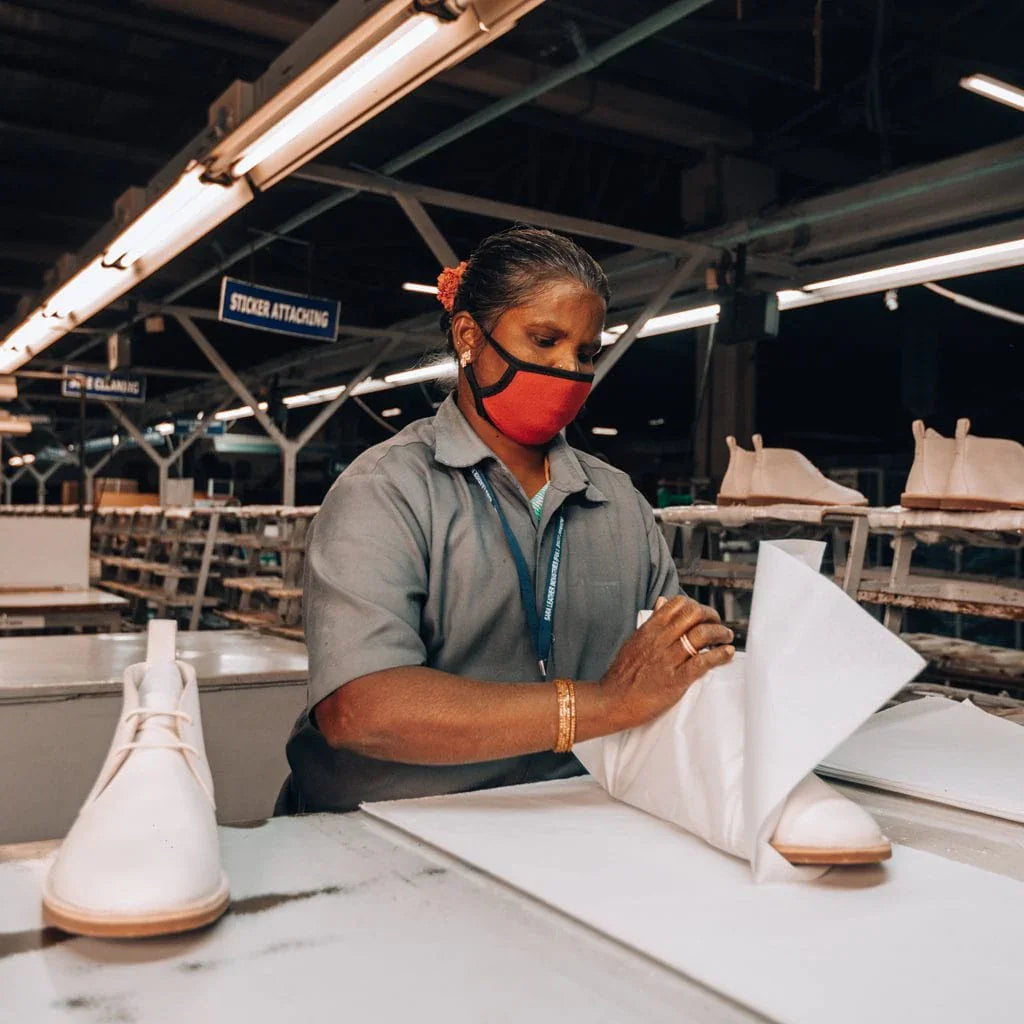 Worker wrapping premium leather footwear in a shoe factory production setting