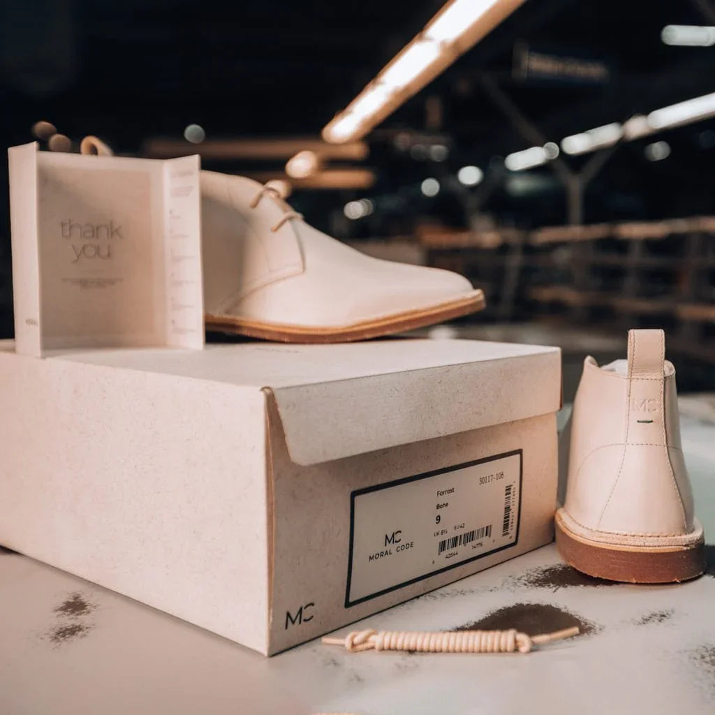 Beige leather chukka boots on shoebox with thank you card, premium men’s footwear setting