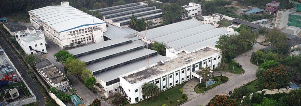 Aerial view of a large footwear manufacturing facility with multiple buildings and greenery.