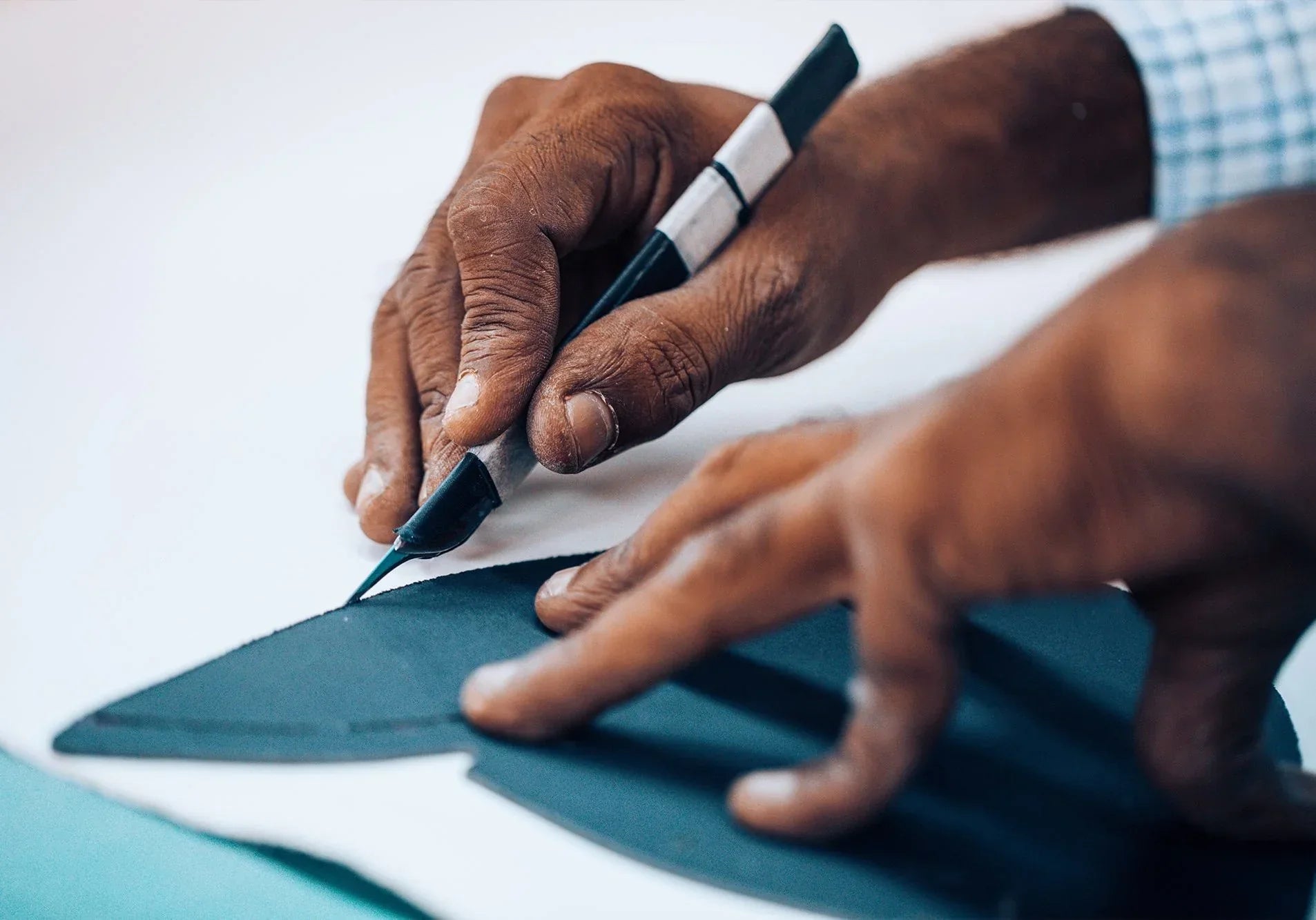 Close-up of hands cutting premium leather for handcrafted footwear