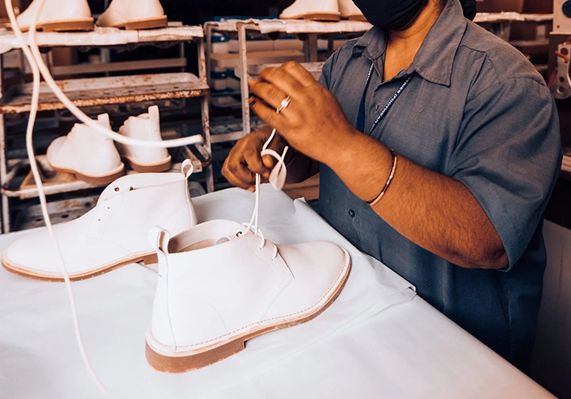 Artisan lacing premium white leather chukka boots in a footwear workshop