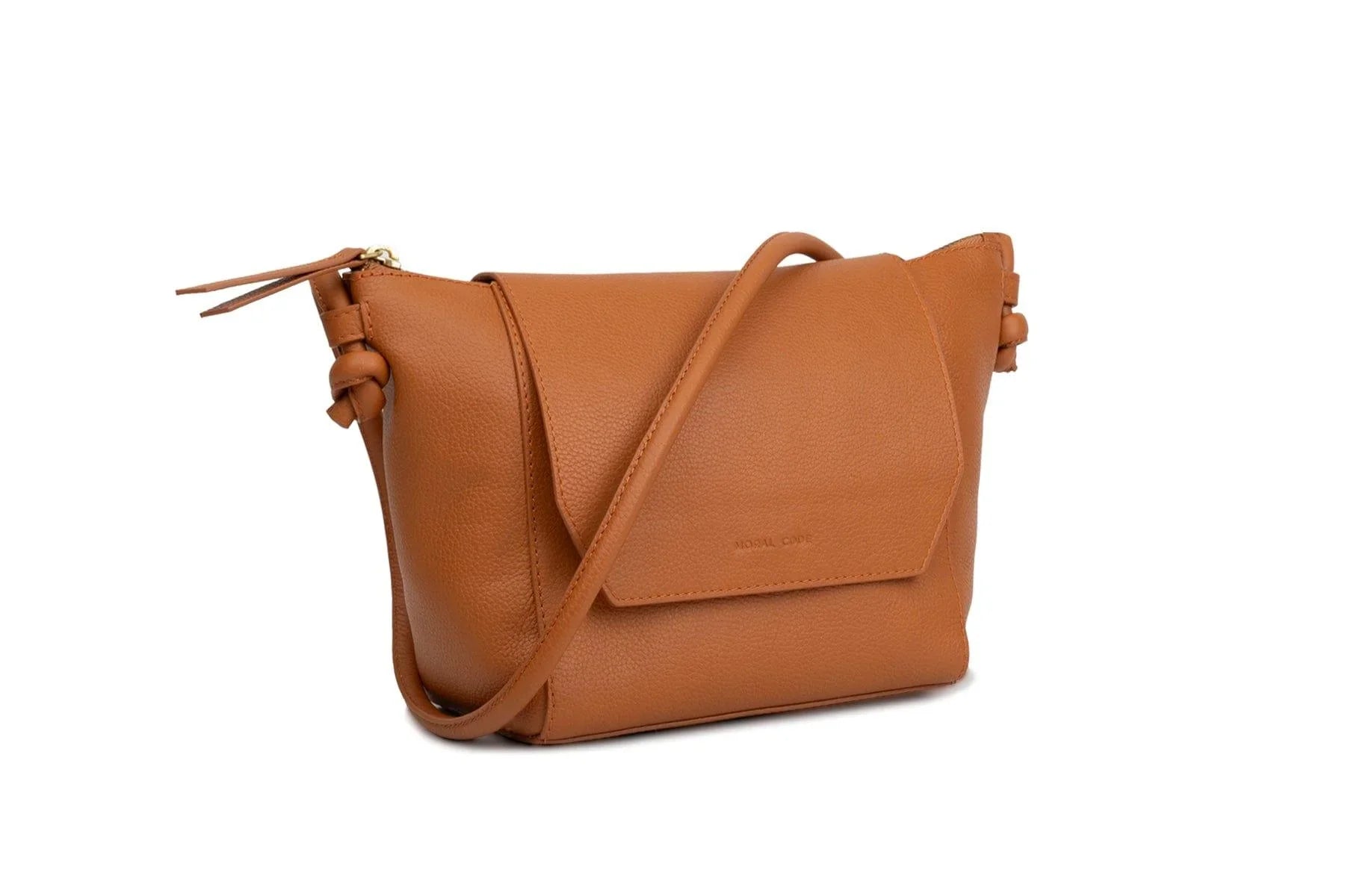 Cognac brown leather crossbody handbag with front flap and adjustable strap on white background