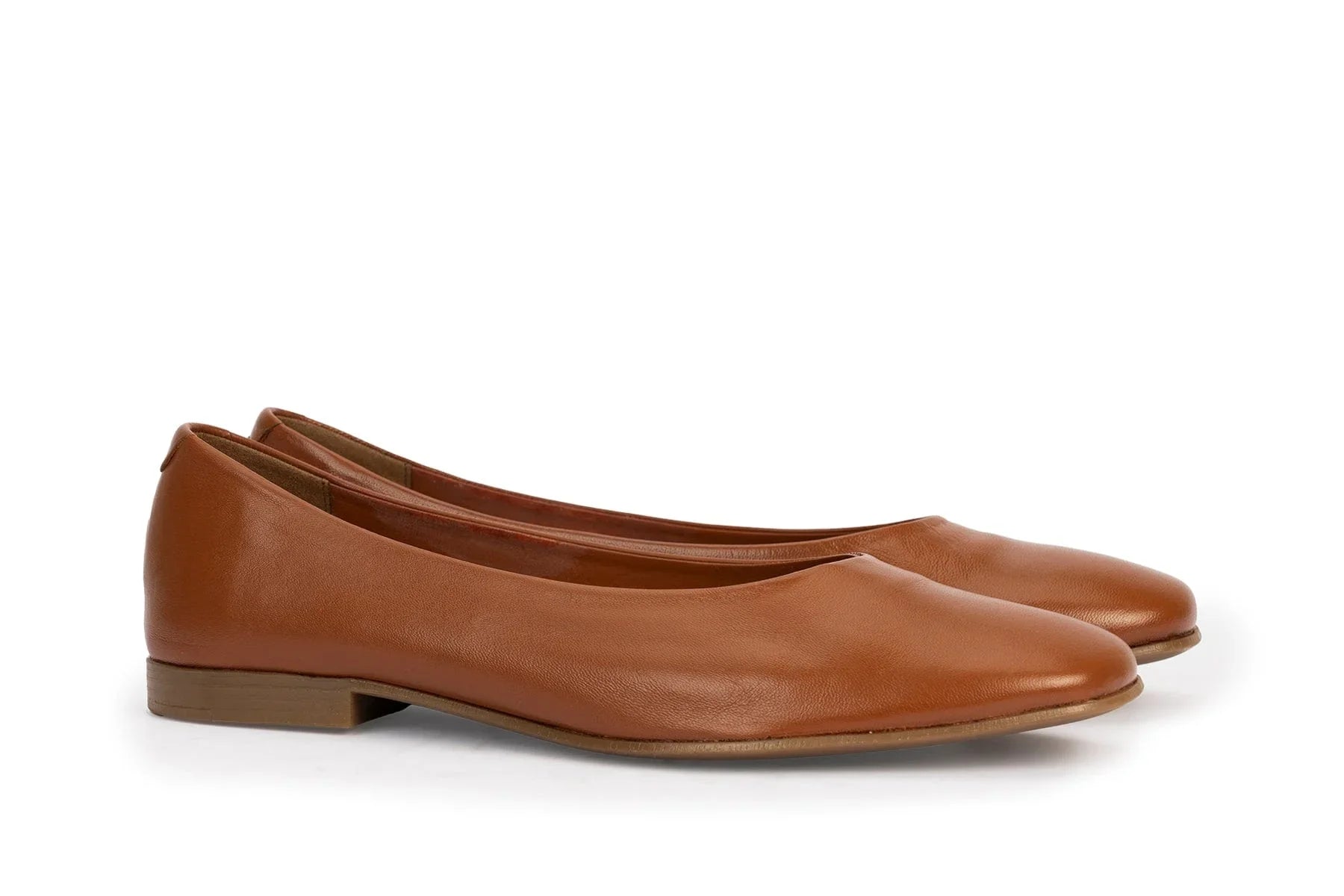 Pair of cognac brown leather ballet flats with low heels on white background