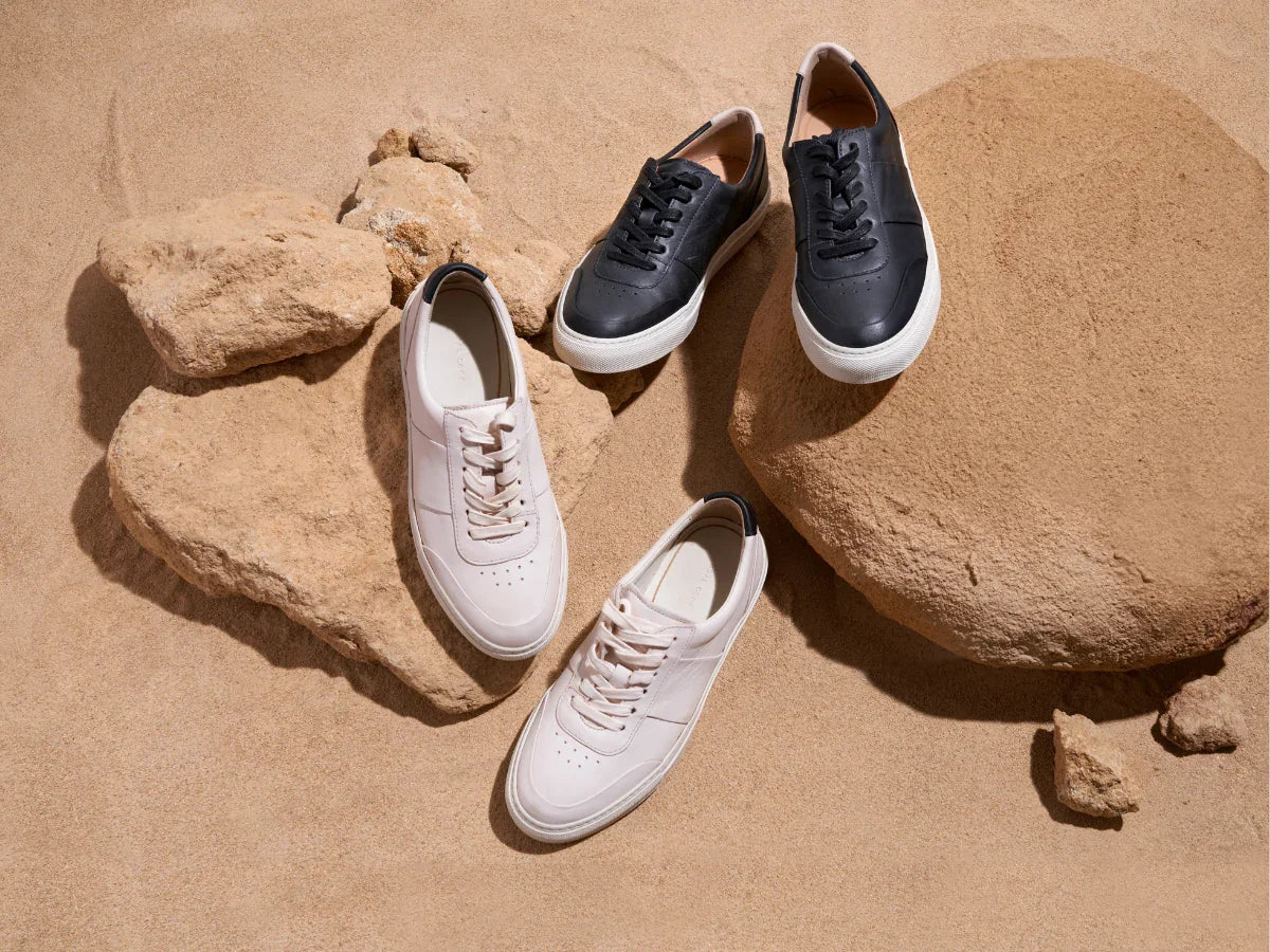 Leather sneakers in black and white on rocks and sand, stylish men's footwear
