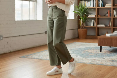 Woman wearing casual white leather sneakers with khaki pants in cozy living room 
