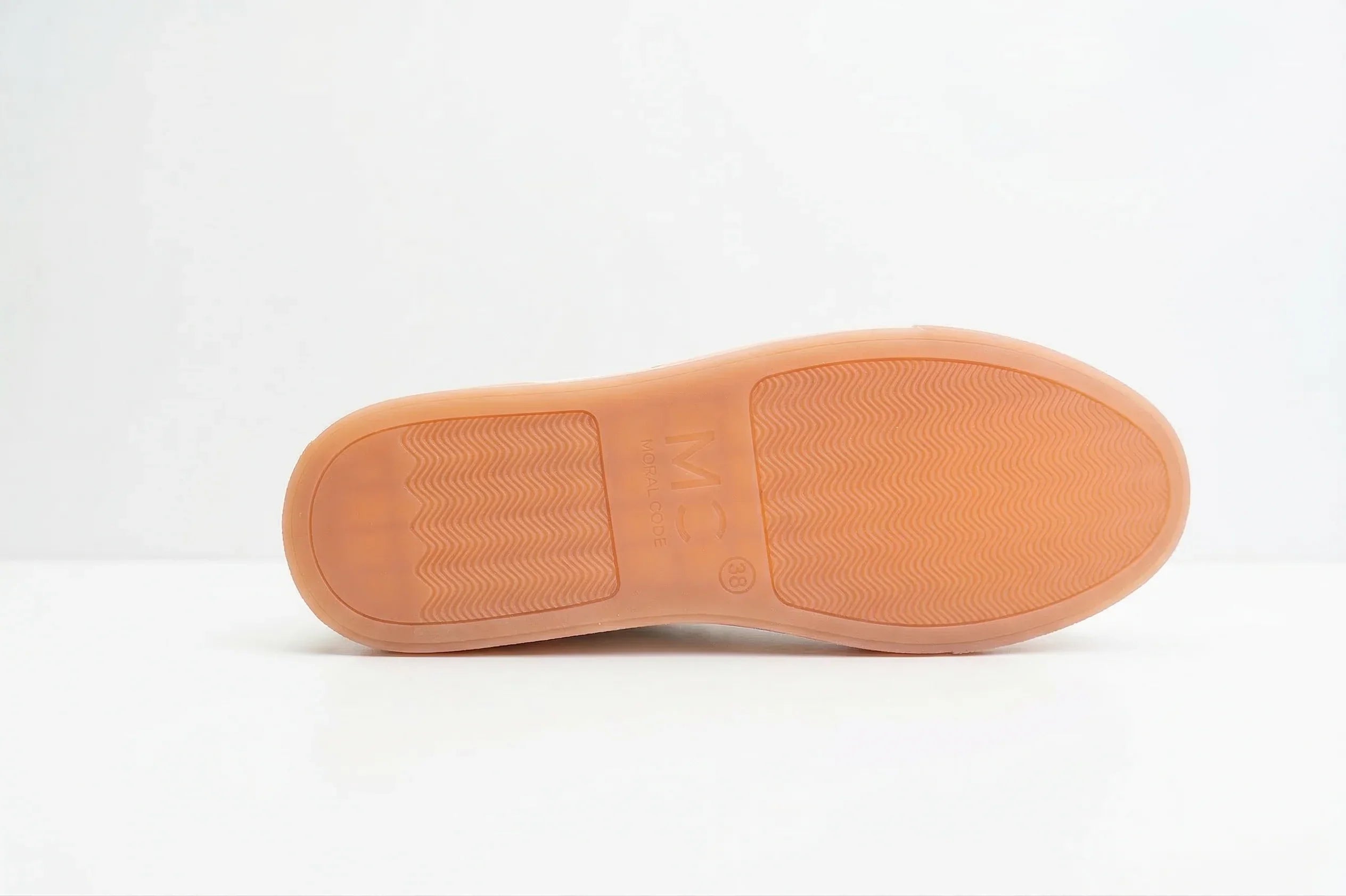 Close-up of tan rubber shoe sole with textured grip pattern on a white background 