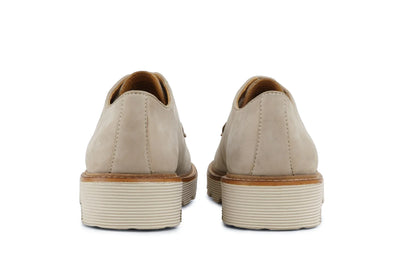 Back view of beige leather dress shoes with stacked ivory soles on white background