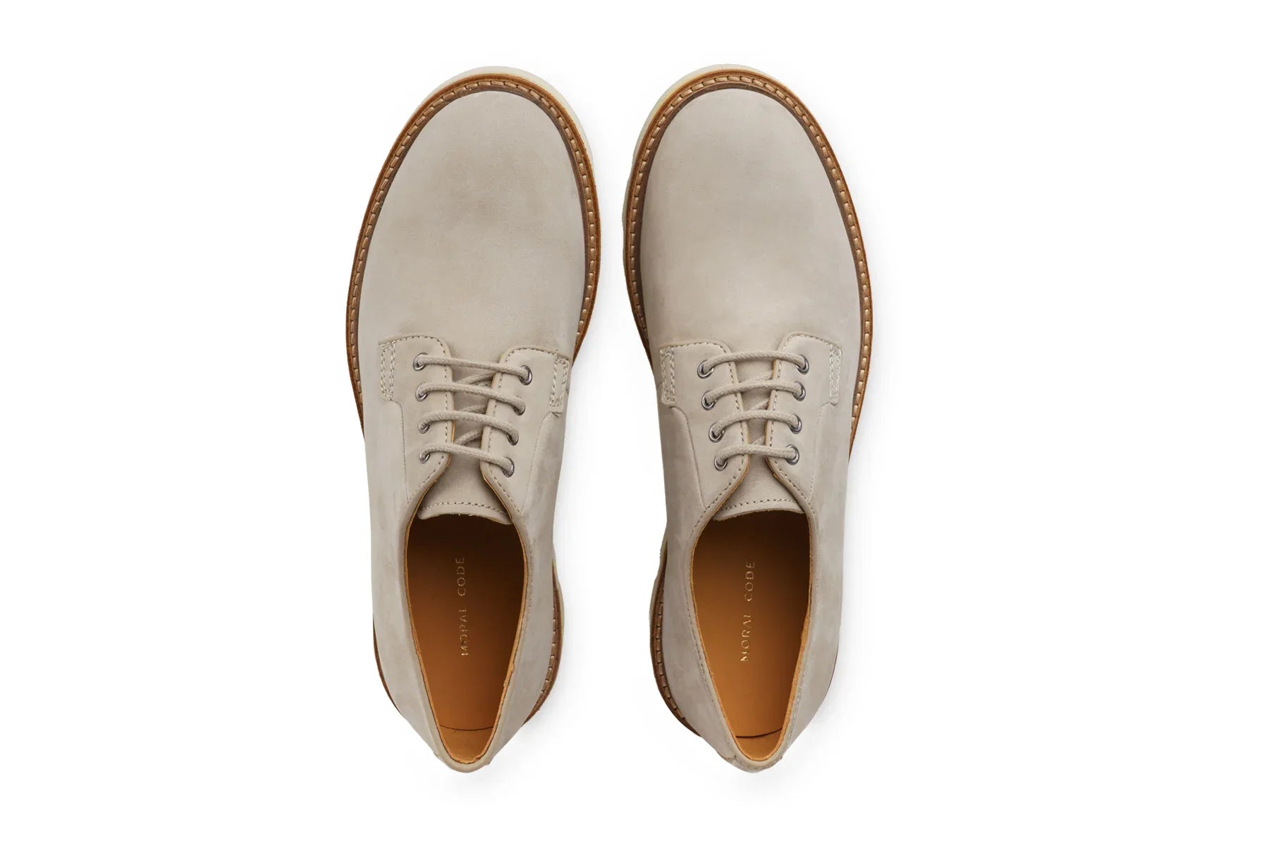 Pair of men's limestone suede leather lace-up dress shoes with brown soles on white background