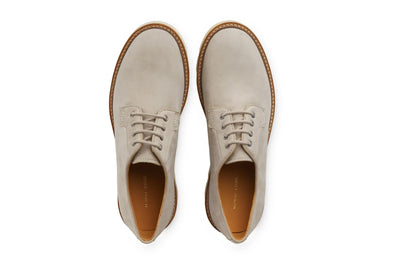 Pair of men's limestone suede leather lace-up dress shoes with brown soles on white background