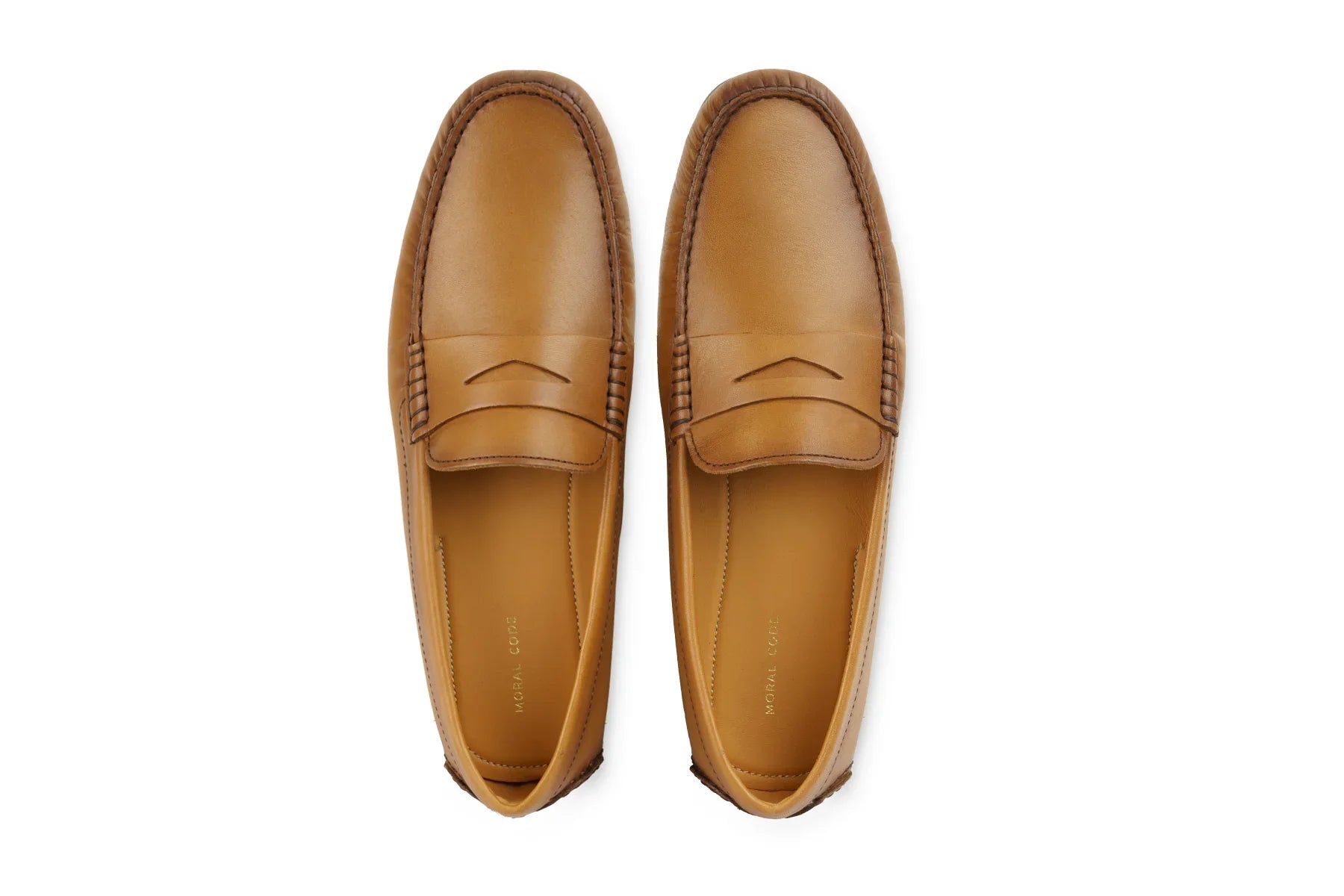 Pair of tan leather penny loafers with stitched detailing, viewed from above on white background 