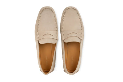 Pair of beige suede penny loafers with stitched details, photographed from above on white background 