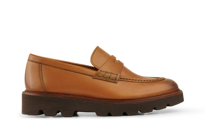 Tan leather loafer with moc toe stitching and chunky brown rubber sole on white background   