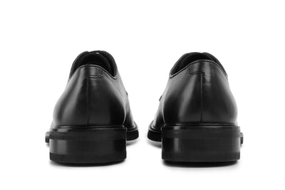 Back view of black leather dress shoes with polished finish on white background  