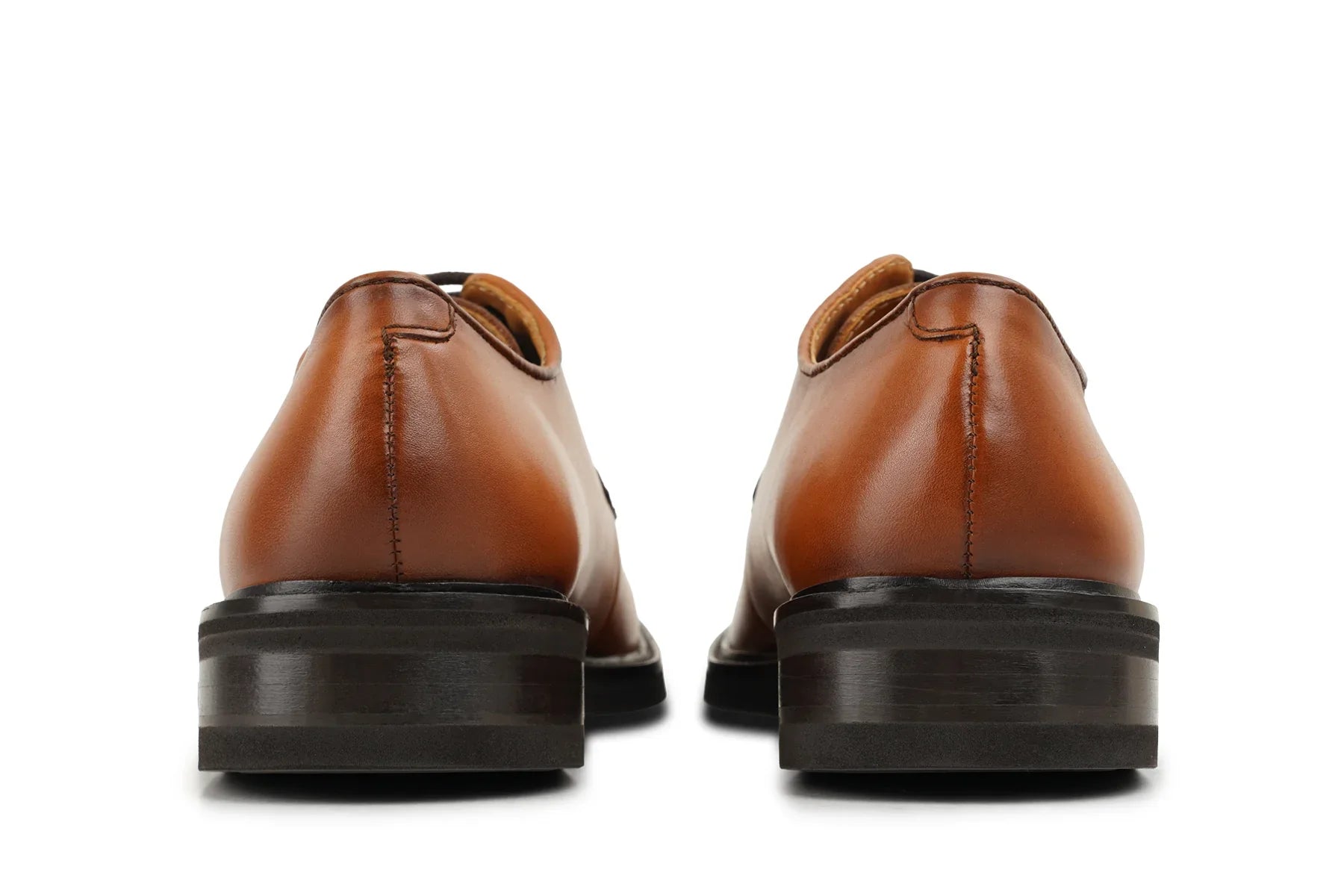 Back view of brown leather dress shoes with stacked heels on white    background     